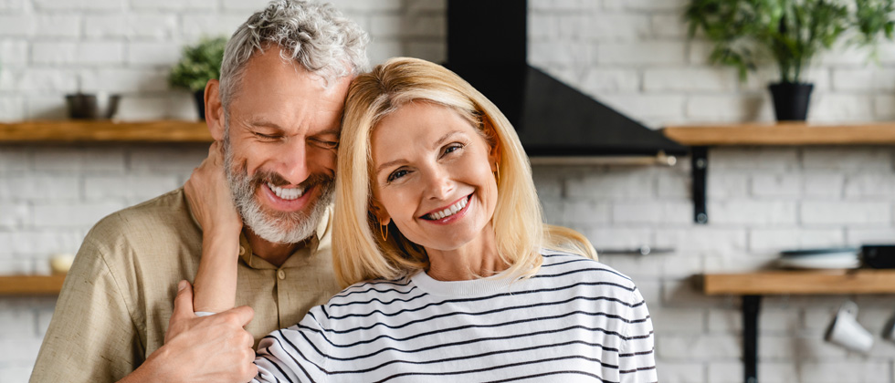 Older happy couple standing in their home holding each other