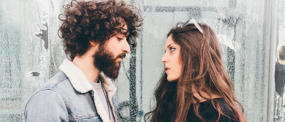 A couple of a woman and a man looking at each other. She seems upset.