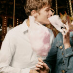 Man and woman eating cotton candy together and laughing as example how to flirt