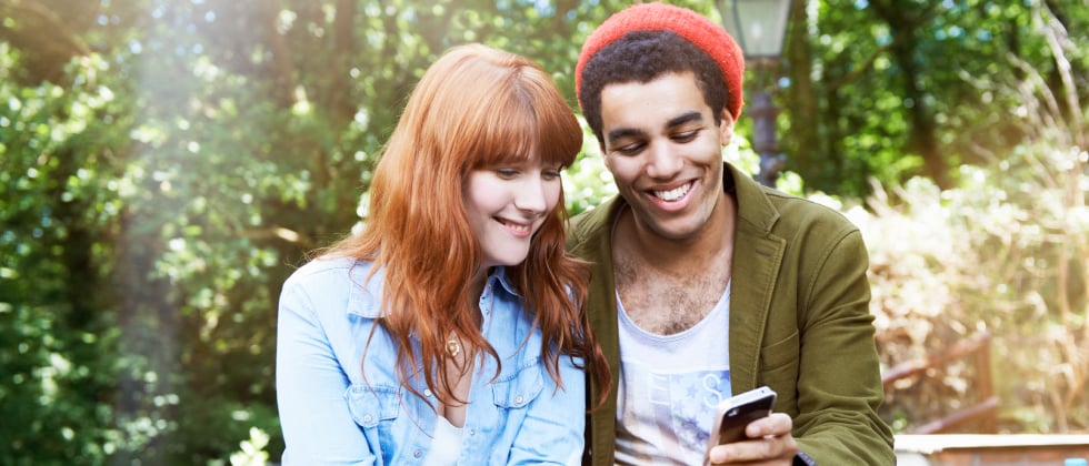 Woman and man looking at a cell phone together as a symbol of dating preferences