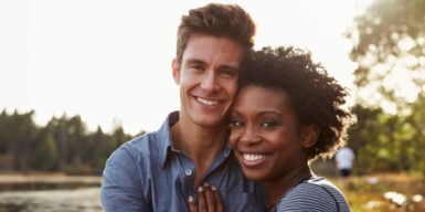 Couple smiling into camera as symbol for interracial relationship