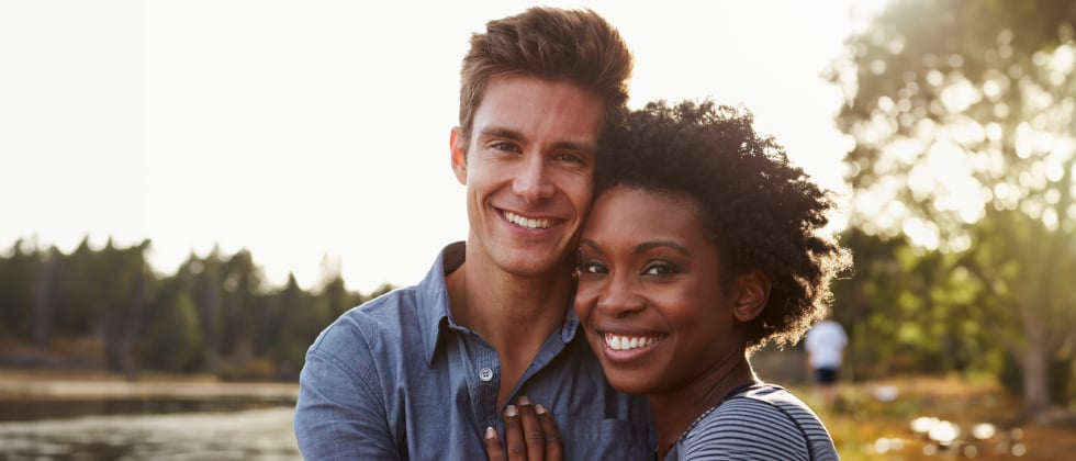 Couple smiling into camera as symbol for interracial relationship