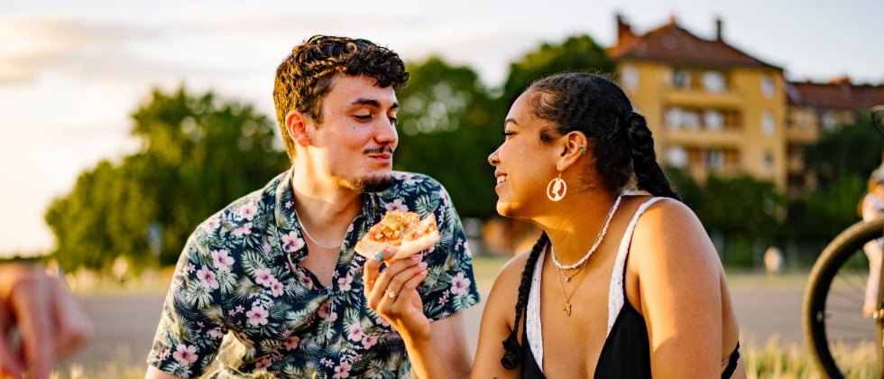 A couple sitting and eating pizza, enjoying quality time together