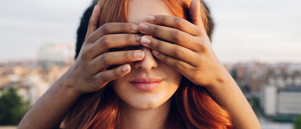 A man covers a womans eyes, telling her words of affirmation