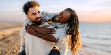 An older woman and a younger man having fun at the beach.