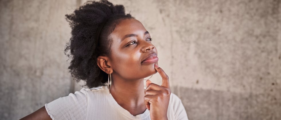 A woman looks thoughtful with her hand cupping her chin.