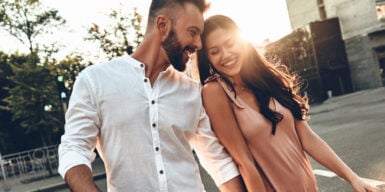 Couple leaning on each other, laughing & holding hands