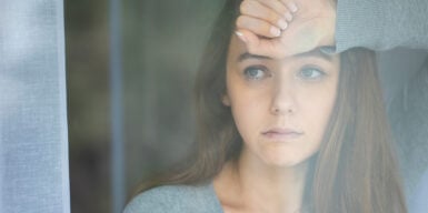 A woman looking concerned while staring out her window